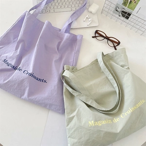 Detailed top view of purple and green canvas tote bags with Magasin de Croissants print