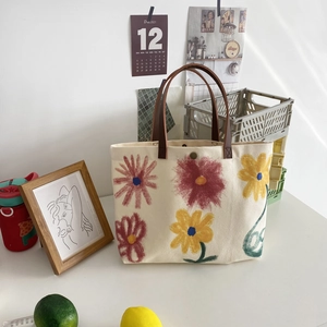 Detailed close-up of canvas tote bag with colorful hand-painted floral patterns on a desk