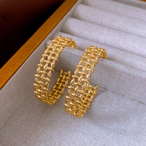 Close-up of gold-plated woven texture hoop earrings in a gray jewelry organizer box