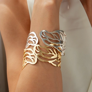 Detailed view of mixed-metal hollow leaf cuff bracelet on model arm with textured fabric