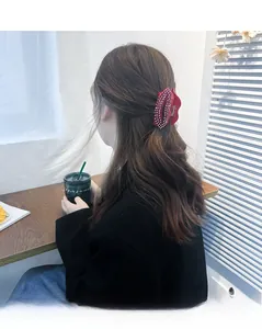 Détail d'une pince à cheveux en forme de lèvres rouges sertie de strass brillants sur modèle