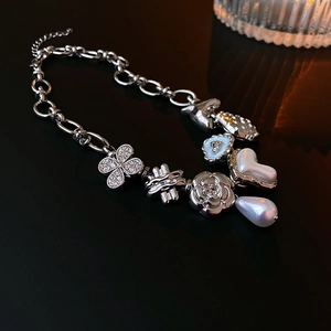 Detailed macro shot of silver necklace with butterfly, heart and pearl charms