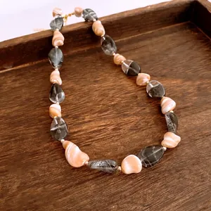 Collier rétro perlé avec perles irrégulières et accents dorés sur plateau bois