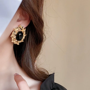 Details von Vintage-Goldohrringen mit ovalen schwarzen Steinen und Blumenmuster