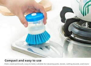 Close-up of a blue palm-sized dish brush with soap dispenser for kitchen cleaning
