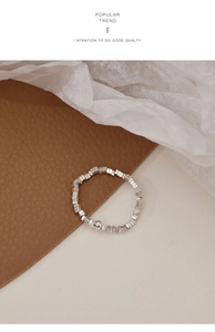Detail of silver square bead elastic ring with a polished round bead on leather