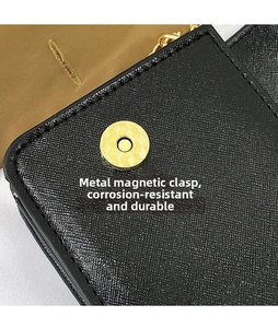 Detail of black Saffiano leather bag featuring golden magnetic closure and metal chain