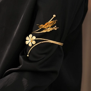 Close-up of golden butterfly and flower cuff bracelet with rhinestones on black sleeve