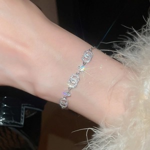 Nahaufnahme eines silbernen Armbands mit ineinandergreifenden Zirkonia-Ringen am Handgelenk