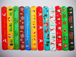 Flat lay of 12 festive Christmas slap bracelets featuring reindeer and Santa patterns