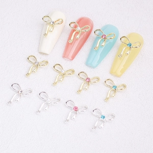 Detail view of hollow alloy bowknot nail charms with colorful rhinestones and pearls