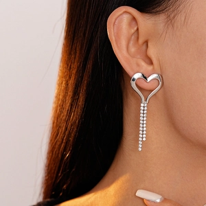 Close-up of heart tassel earrings with sparkling rhinestones worn on a model