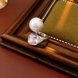 Detailed view of an open ring featuring a large pearl and a square pink crystal gem