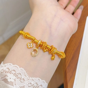 Detail of 24k gold beaded bracelet with clover charm and oval gem pendant on wrist