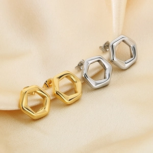 Detail view of hexagonal hollow earrings in gold and silver on silk background