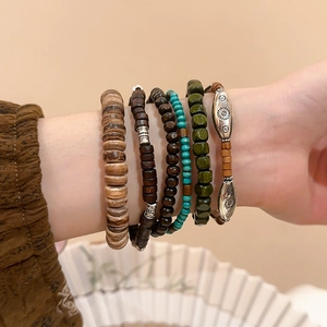 Detail of stacked bohemian bracelets with wood beads and vintage silver sun charms