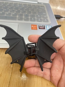 Detail shot of a black bat wing hair claw clip held in hand against a desktop
