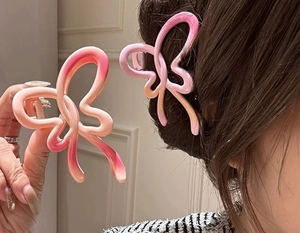 Detailed view of hollow butterfly hair claw clips in gradient pink and orange finishes