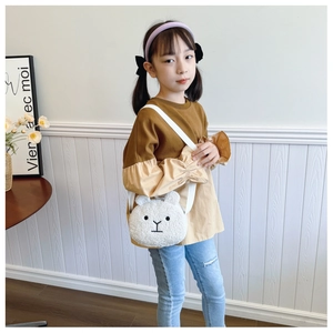 Detail of child wearing a cute white plush polar bear crossbody bag with fluffy texture