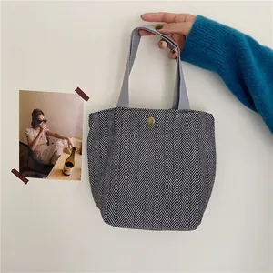 Close-up of retro herringbone wool tote bag with grey ribbon handles and bronze button