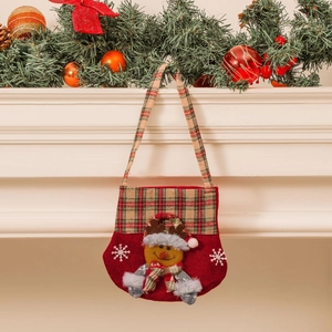 Christmas reindeer plaid gift bag with plush antlers hanging on a festive decorated fireplace
