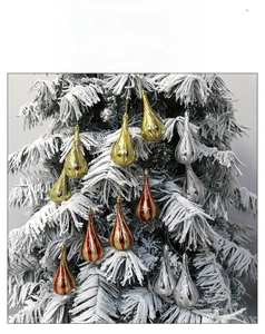 Detailed view of silver and gold teardrop Christmas ornaments hanging on snowy tree branches