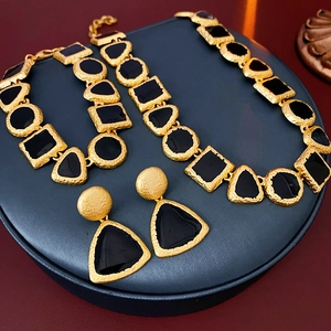 Detailed view of vintage geometric necklace and earrings set on blue jewelry display stand