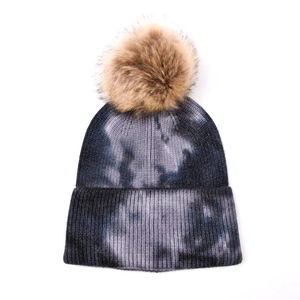 Détails de la maille du bonnet d'hiver tie-dye avec un grand pompon en fausse fourrure