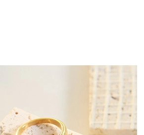 Close-up of a thick minimalist 18K gold plated stainless steel ring on a textured stone