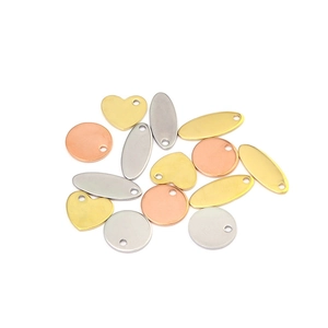 Macro detail of heart and oval steel charms in gold, silver, and rose gold finishes