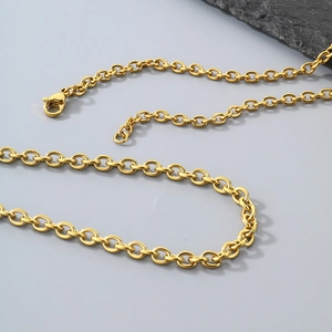 Macro detail of golden stainless steel O-chain necklace links on grey background