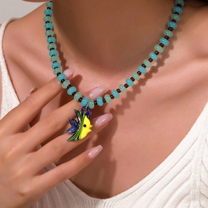 Dettaglio della collana di perline con elementi marini blu e pendente a forma di pesce