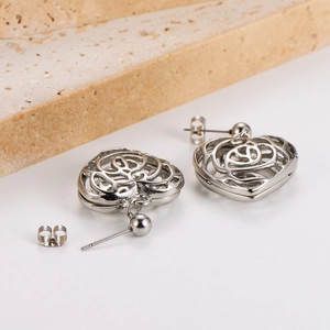 Detailed close-up of silver stainless steel heart stud earrings with rose motif on stone