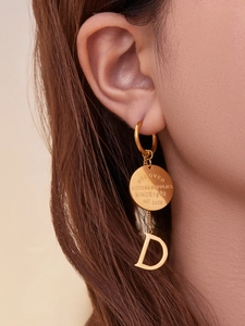 Détail de boucles d'oreilles créoles dorées 18K avec disque gravé et pendentif lettre D