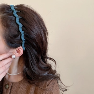 Détail d'un serre-tête plissé bleu sur cheveux bruns pour un effet de sommet haut