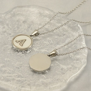 Polished silver stainless steel necklace with round initial A pendant on glass tray