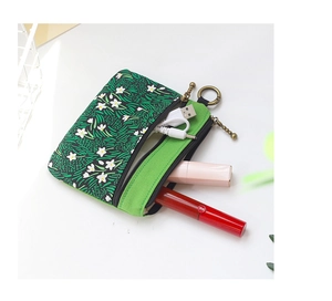 Détail de la pochette en toile fleurie verte montrant la double fermeture pour petits objets