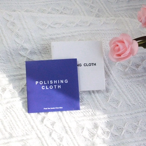 Polishing cloth for silver and gold jewelry in purple and white packaging on white blanket