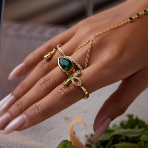 Detail of vintage 18K gold slave bracelet with green emerald zircon and Ankh cross