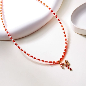 Detail of beaded Christmas necklace with candy cane and gold bow pendant elements