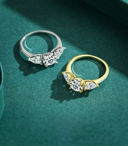 Detail of silver and gold S925 rings featuring three-stone design with pear-cut side stones