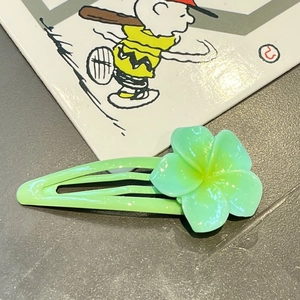 Detailed close-up of a green flower hair clip with semi-transparent petals and yellow center