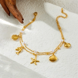 Detail of gold layered anklet with shell, dolphin pendants and small pearls