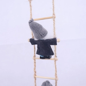 Detail of wool felt gnome climbing a wooden rope ladder for Christmas fireplace decor