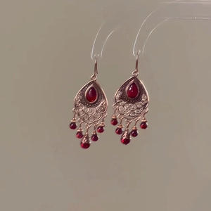 Gros plan détaillé de boucles d'oreilles en cuivre rétro avec pierre rouge et franges