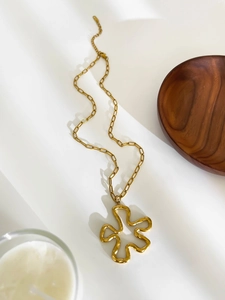 Detail of a large gold abstract flower pendant on a bold titanium steel chain necklace
