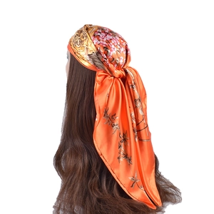Dettaglio di un foulard in raso arancione a fiori con trama liscia e drappeggio elegante