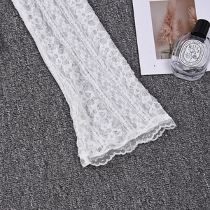 Detailed close-up of intricate white floral lace texture on flared long sleeves