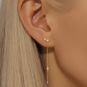 Detail of gold moon and star drop earrings with zircons worn by a female model