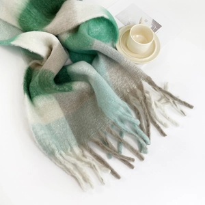 Macro detail of thick mohair scarf featuring green and white plaid pattern with soft fringes